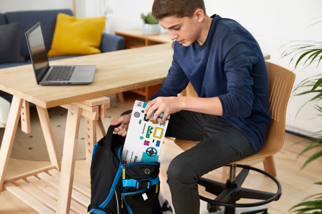 Zestaw LEGO Personal Learning Kit Prime chłopiec wyjmuje z torby i przygotowuje się do nauki przy komputerze