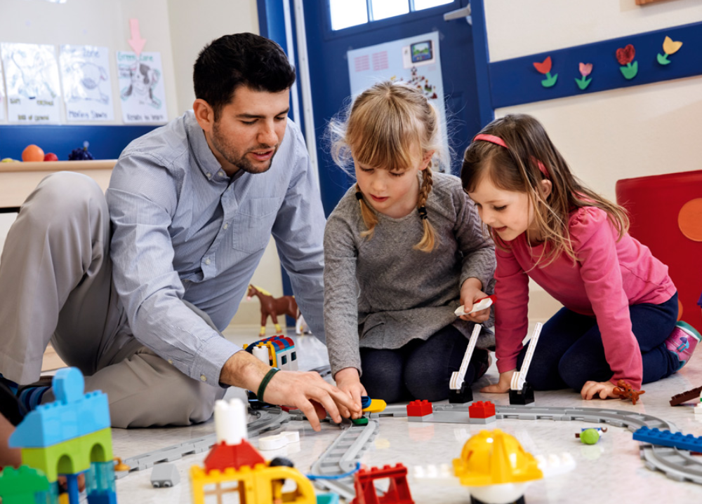 nauczyciel buduje z dziewczynkami model z klocków LEGO education w przedszkolu